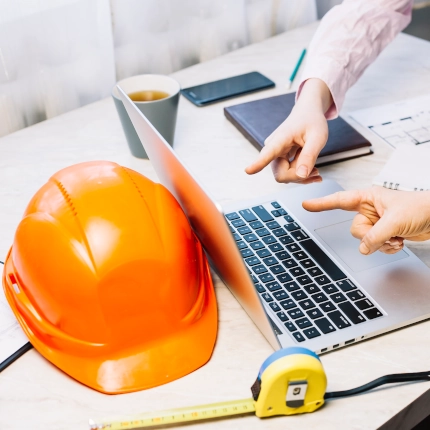 Un ordinateur avec un casque de chantier posé à côté